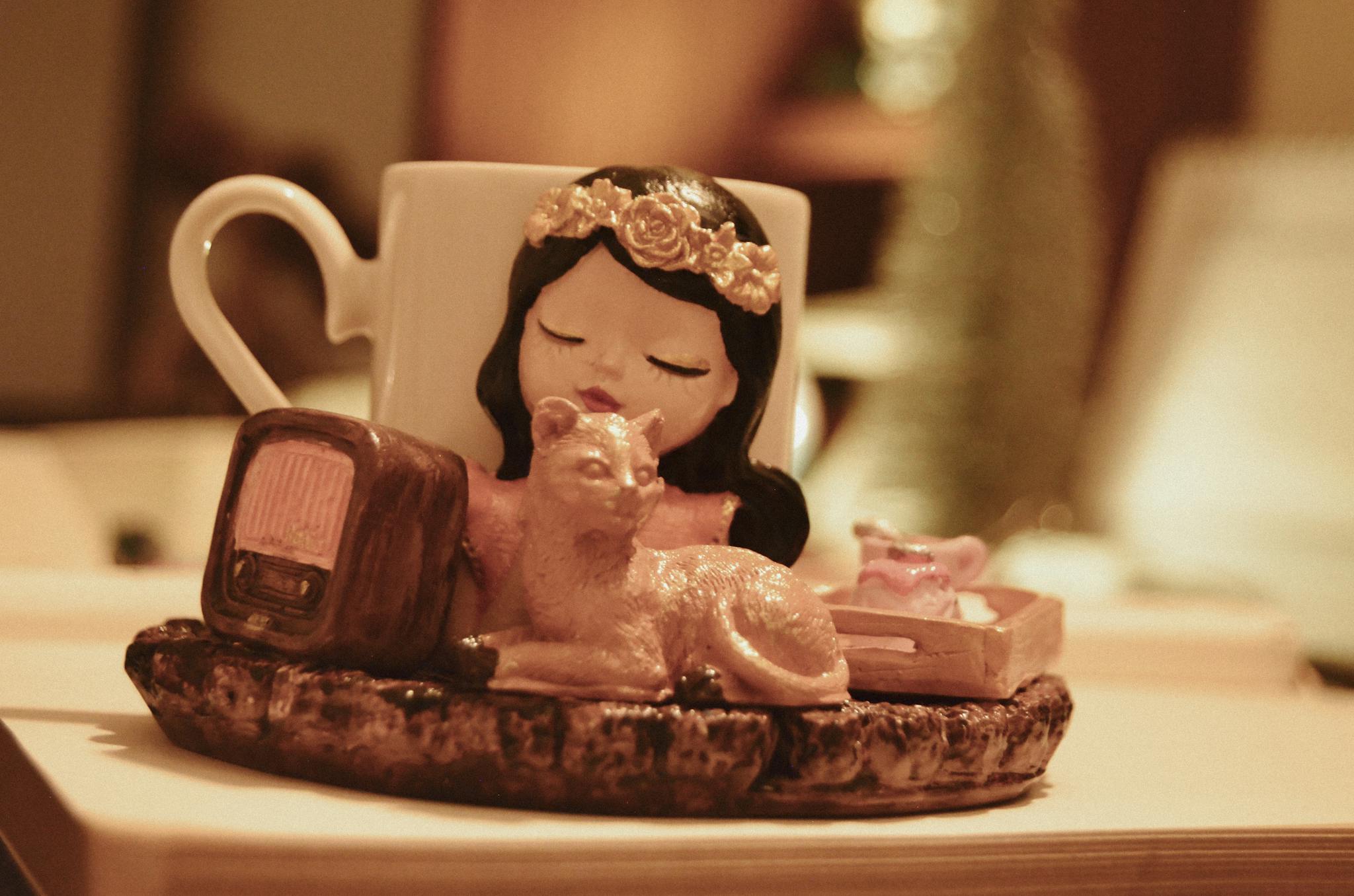 Artistic figurine with cat and mug on a tabletop, perfect for home decor inspiration.